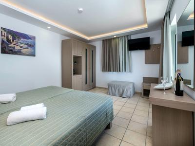 Nowoczesny pokój hotelowy z łóżkiem, szafą, telewizorem i biurkiem z lustrem.