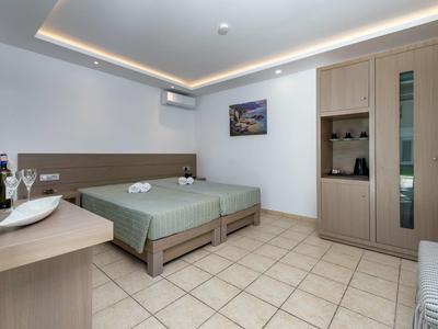 Nowoczesny pokój hotelowy z podwójnym łóżkiem, kafelkową podłogą, drewnianymi meblami i miękkim oświetleniem.