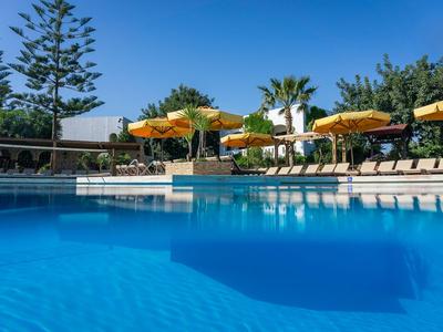 Grande piscina con lettini e ombrelloni davanti a un edificio dell'hotel in una giornata di sole