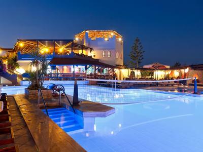 Piscina esterna illuminata e area salotto di notte in un resort alberghiero.