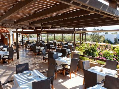 Überdachte Hotelterrasse mit gedeckten Tischen und Ausblick auf Garten und Poolbereich.