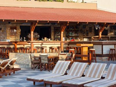 Außenbereich eines Hotels mit Liegestühlen und Bartresen unter einem Sonnendach.