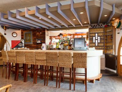 Barbereich mit hohem Tresen und geflochtenen Holzstühlen in einem gemütlichen Hotelrestaurant.