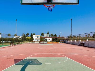 Leerer Basketballplatz mit klarem Himmel und Ferienhäusern im Hintergrund.