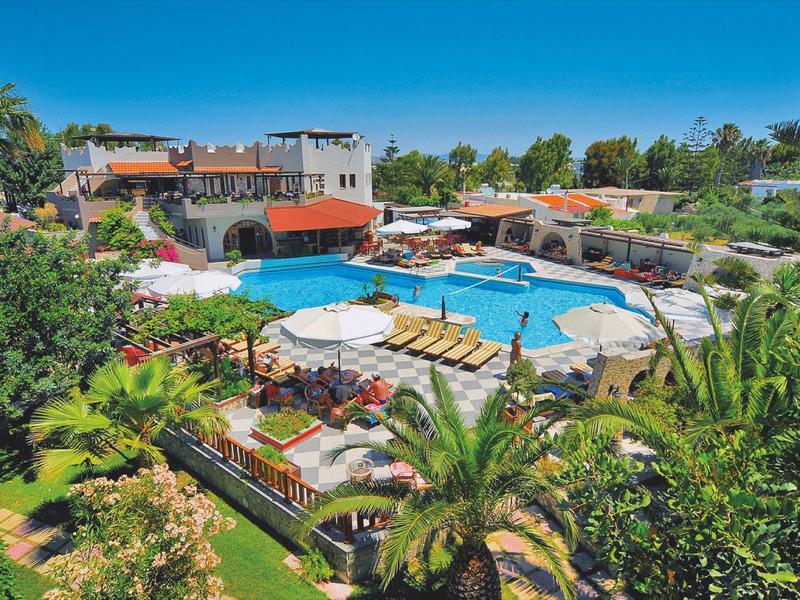 Basen na świeżym powietrzu otoczony leżakami, parasolami i bujną zielenią w ośrodku.