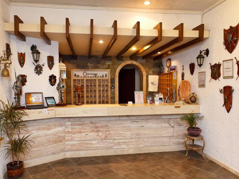 Recepcja hotelowa z drewnianymi belkami, kamiennym konturem i dekoracyjnymi tablicami na ścianach.