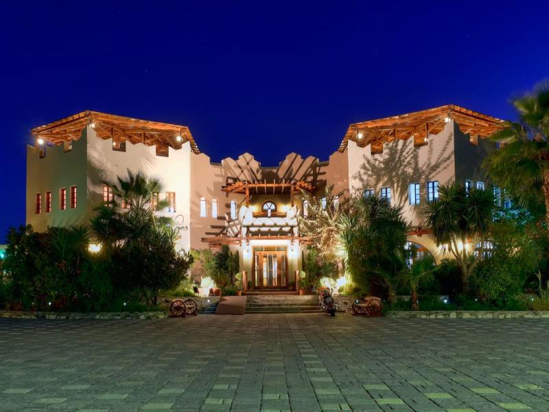 Luksusowy hotel oświetlony nocą z palmami i dekoracyjnym oświetleniem.