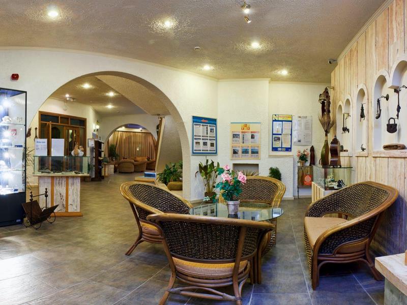 Przytulna recepcja hotelowa z wyplatanym meblami, wystawami sztuki i ciepłym oświetleniem.