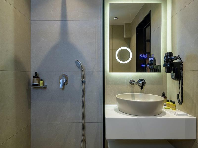 Nowoczesna łazienka z prysznicem bez brodzika, dużym lustrem i umywalką na blacie.