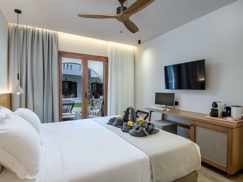 Nowoczesny pokój hotelowy z podwójnym łóżkiem, balkonem, telewizorem, biurkiem i ekspresem do kawy.