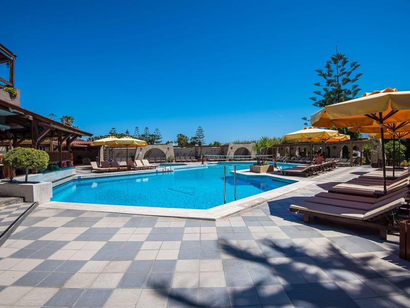 Basen na zewnątrz z leżakami i parasolami pod czystym niebem w ośrodku wypoczynkowym.