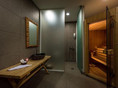 Modern spa area with sauna, shower, and wooden table with towels.