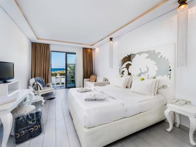 Camera d'hotel moderna con letto matrimoniale, TV a schermo piatto e balcone con vista sul mare.