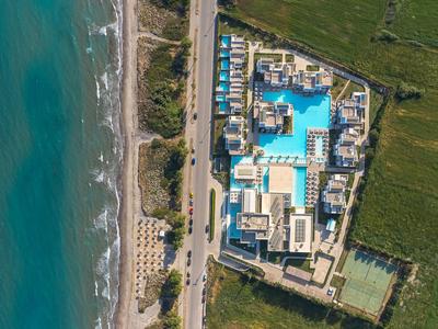 Aerial view of a resort with pool, spa area, and adjacent beach.