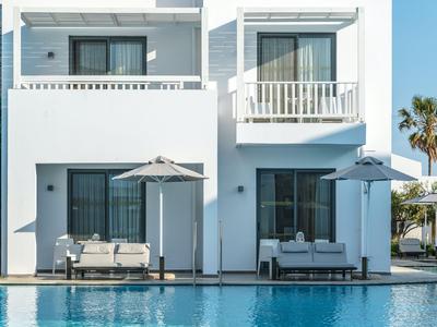 Due appartamenti bianchi moderni con balconi e aree salotto vicino alla piscina in una giornata limpida.