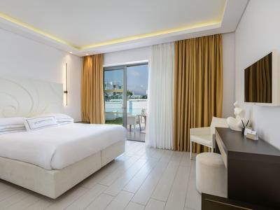 Modern hotel room with double bed, balcony, and wall-mounted TV.