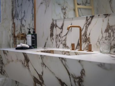 Modern bathroom sink with gold faucet and marble countertop.