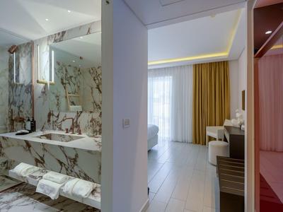 Modern hotel bathroom area with marble tiles and adjacent living space.
