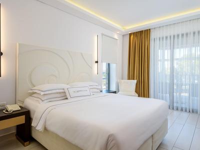 Bright hotel room with large bed, curtains, and modern lighting