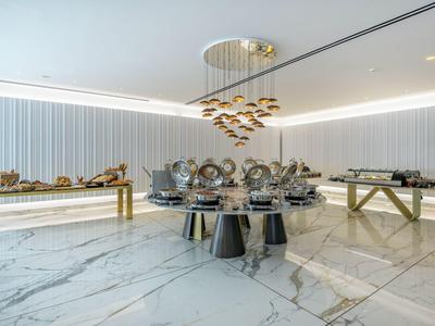 Elegante buffet con piatti caldi in una stanza moderna con pavimento in marmo e illuminazione a soffitto.