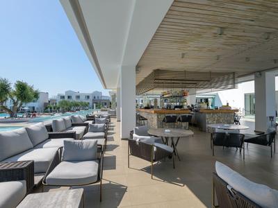 Zona esterna di un bar di hotel moderno con posti a sedere e vista sulla piscina.