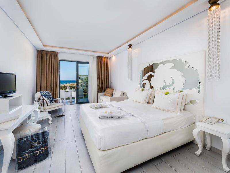 Modern hotel room with double bed and balcony overlooking the sea.