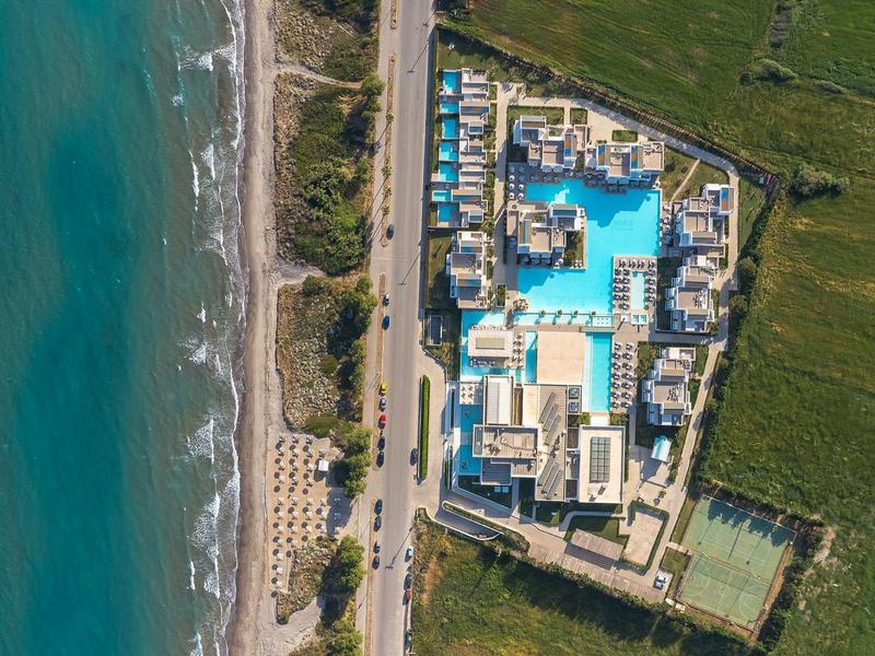 Aerial view of a resort with pool, spa area, and adjacent beach.