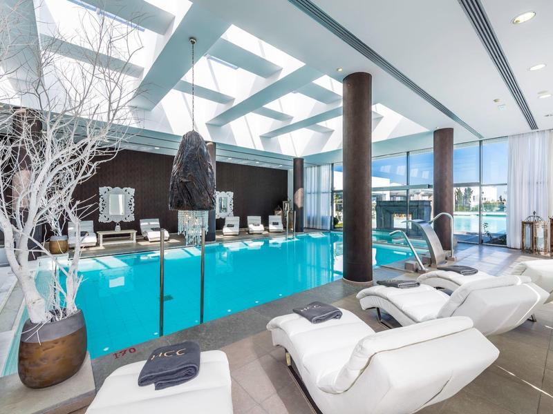 Modern wellness area with pool, lounge chairs, and large windows for natural light.