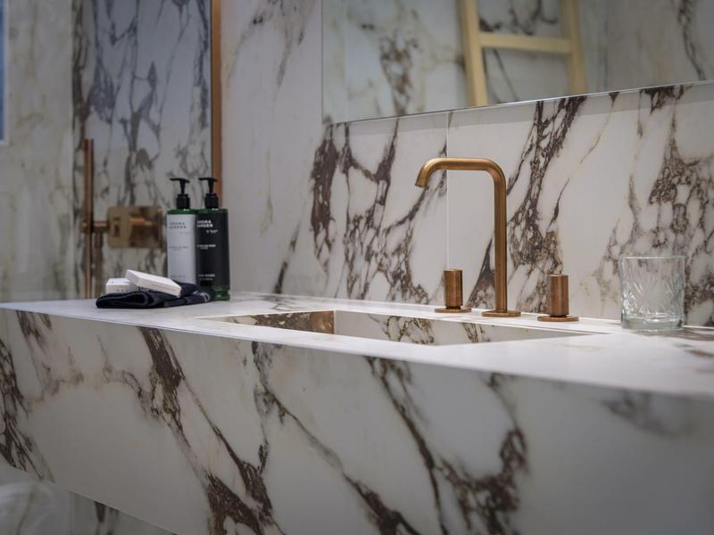 Modern bathroom sink with gold faucet and marble countertop.