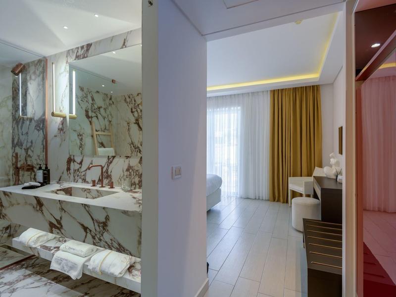 Modern hotel bathroom area with marble tiles and adjacent living space.