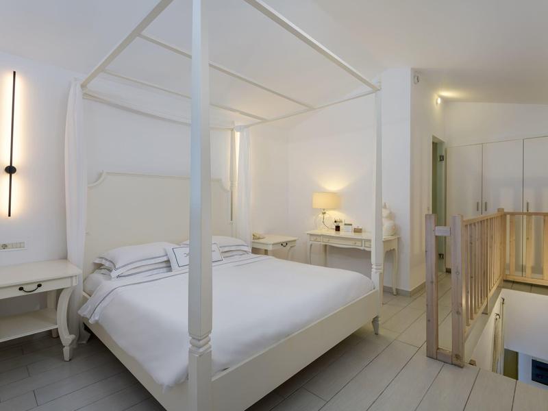 Bright bedroom with white canopy bed and modern furniture in a hotel room.