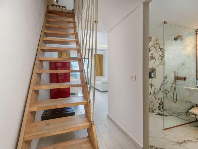 Modern interior with wooden spiral staircase and elegant bathroom in the background.