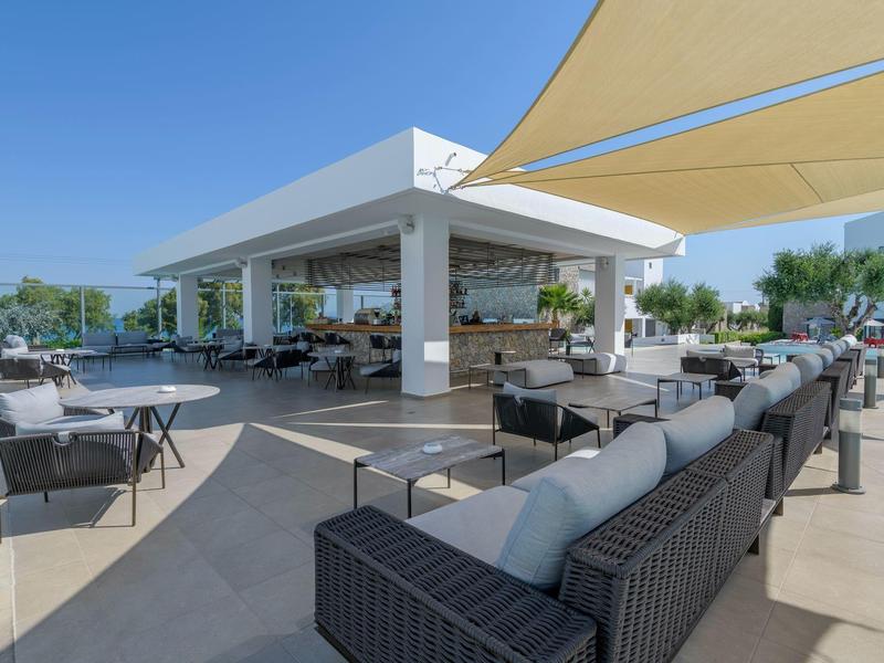 Modern terrace with comfortable seating furniture and sunshade sails under clear sky.