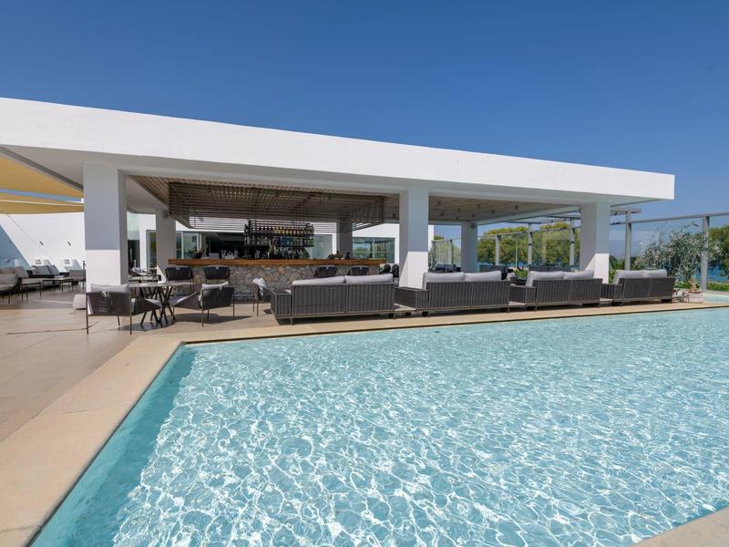 Modern outdoor pool with lounge area and clear sky at a hotel.
