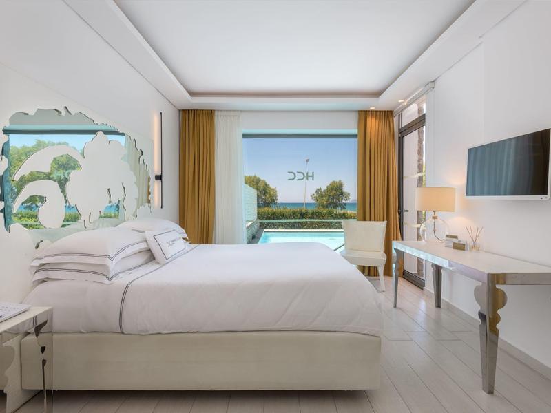 Modern hotel room with large bed, window overlooking lake, and minimalist decor.