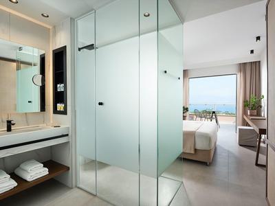 Moderner heller Wohnraum mit Glas-Dusche, Waschbecken und Meerblick im Hintergrund.