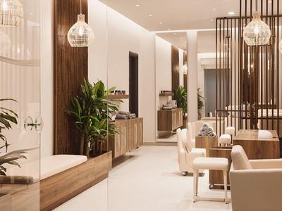 Moderne Lounge mit hellen Tönen, Holzwerken, Pflanzen und eleganten Sitzbereichen.