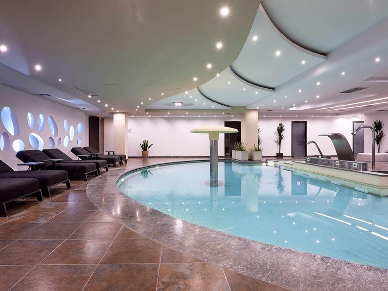 Interno di una moderna piscina benessere con lettini e illuminazione soffusa.