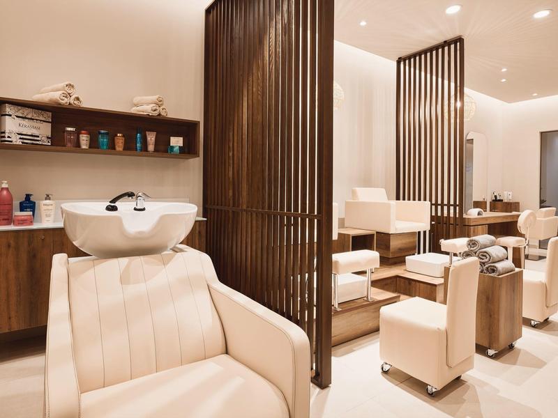 Salone di bellezza moderno con poltrone beige ed eleganti elementi in legno.