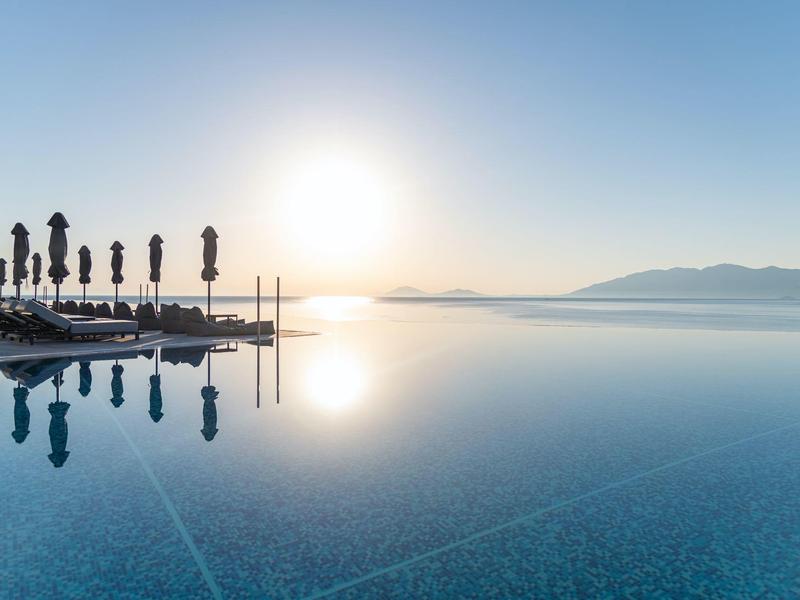 Vista di una piscina a sfioro con tramonto e montagne sullo sfondo