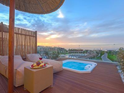 Terrasse mit Lounge-Sofa und kleinem Pool mit Blick auf Landschaft und Sonnenuntergang.