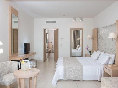 Modern hotelkamer met tweepersoonsbed, zithoek en uitzicht op aangrenzende kamers.