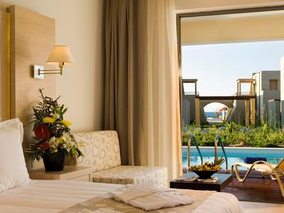 Lichte hotelkamer met uitzicht op een zwembad en comfortabele meubels.