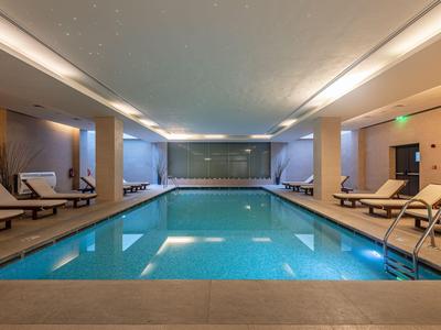 Modern heated indoor pool with lounge chairs on the sides in a hotel