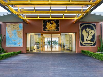 Entrance area of a modern building with golden roof and large glass entrance doors.