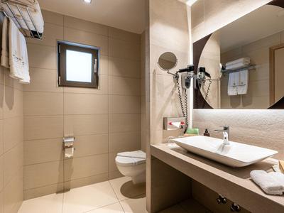 Modern bathroom with toilet, sink, and round mirror in neutral tones.