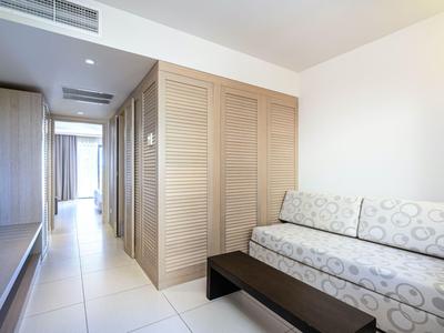 Modern hotel room area with sofa, wardrobe, and bright corridor lighting.