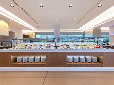 Modern buffet with various dishes in a bright, spacious restaurant.