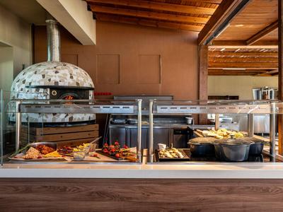 Buffet with various hot dishes in a restaurant with wooden beam ceiling.