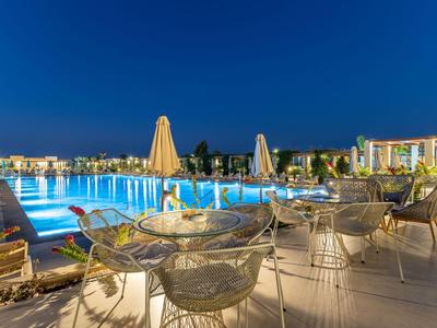 Illuminated pool with outdoor seating and umbrellas at night in a hotel.